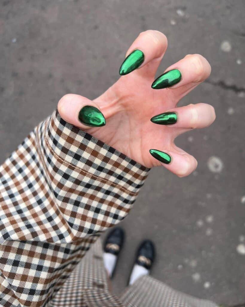 Hands displaying different metallic nail styles, featuring black nails with silver specks, dark gold polish, and shiny red acrylic nails.