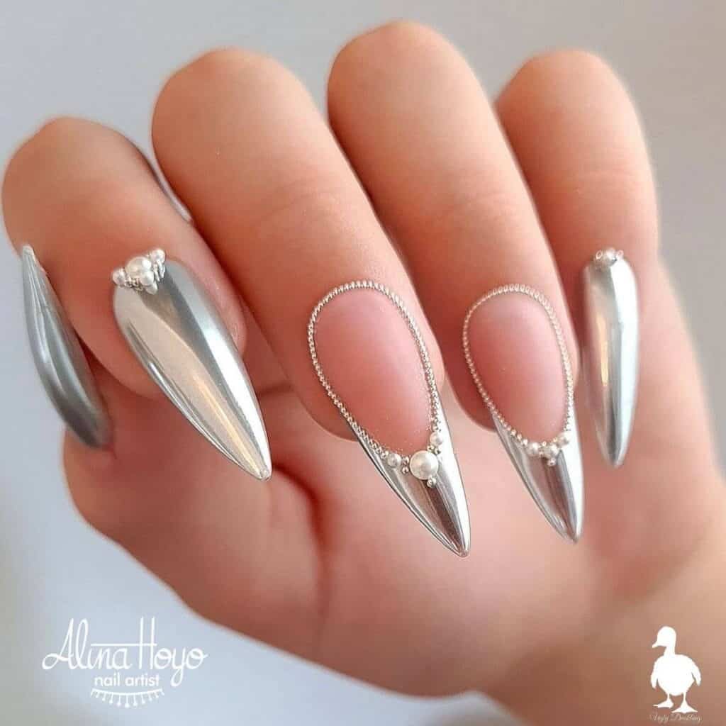 Hands displaying different metallic nail styles, featuring black nails with silver specks, dark gold polish, and shiny red acrylic nails.