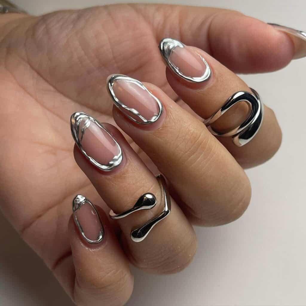 Hands displaying different metallic nail styles, featuring black nails with silver specks, dark gold polish, and shiny red acrylic nails.